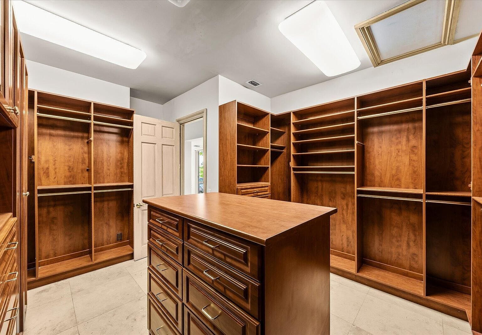 Enormous walk-in closet with dark wood shelving and a center island dresser