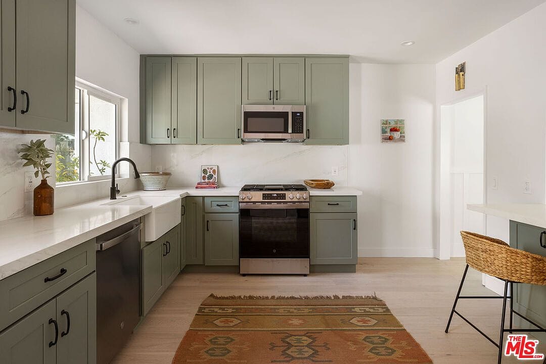 Kitchen stove area with stainless steel range and a patterned floor rug