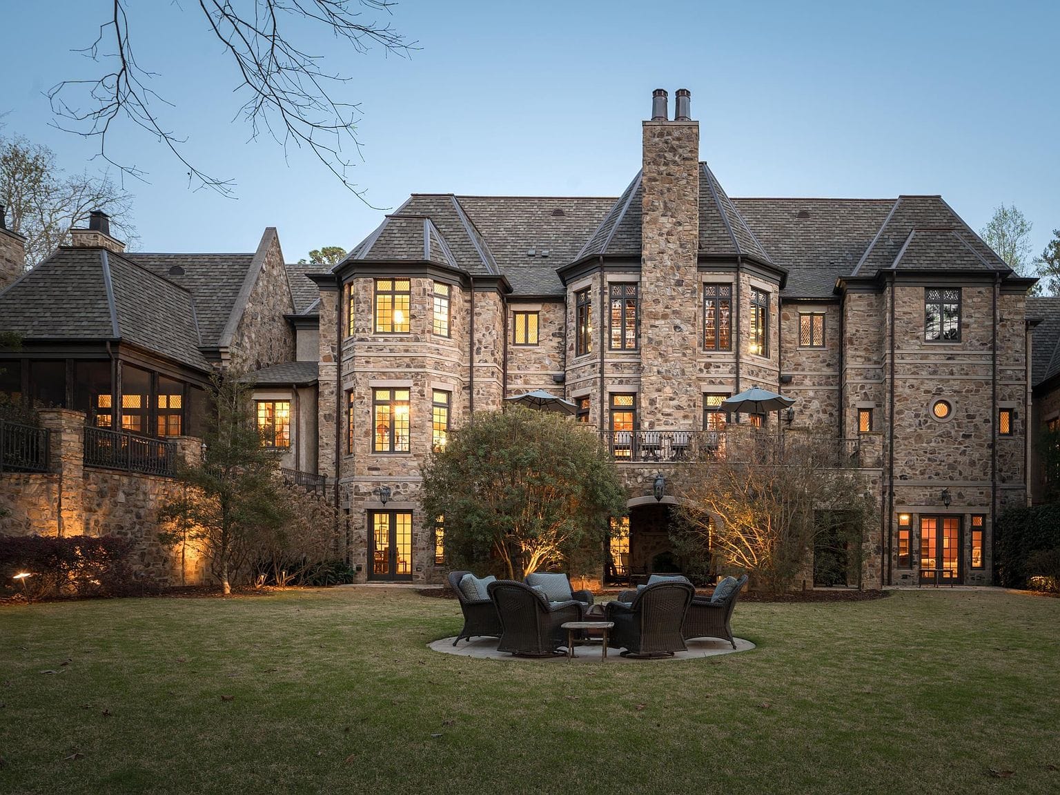 The rear exterior of the stone home lit up at night