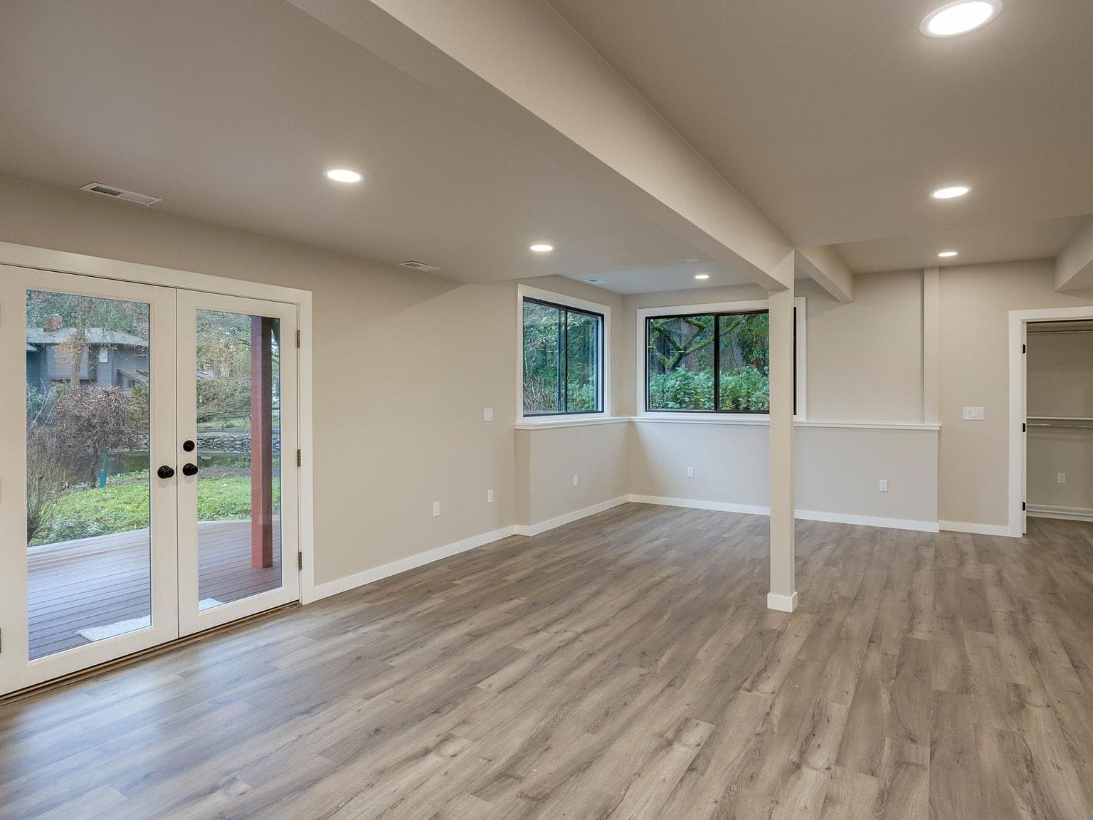 Finished basement, white walls, wood floors, French doors