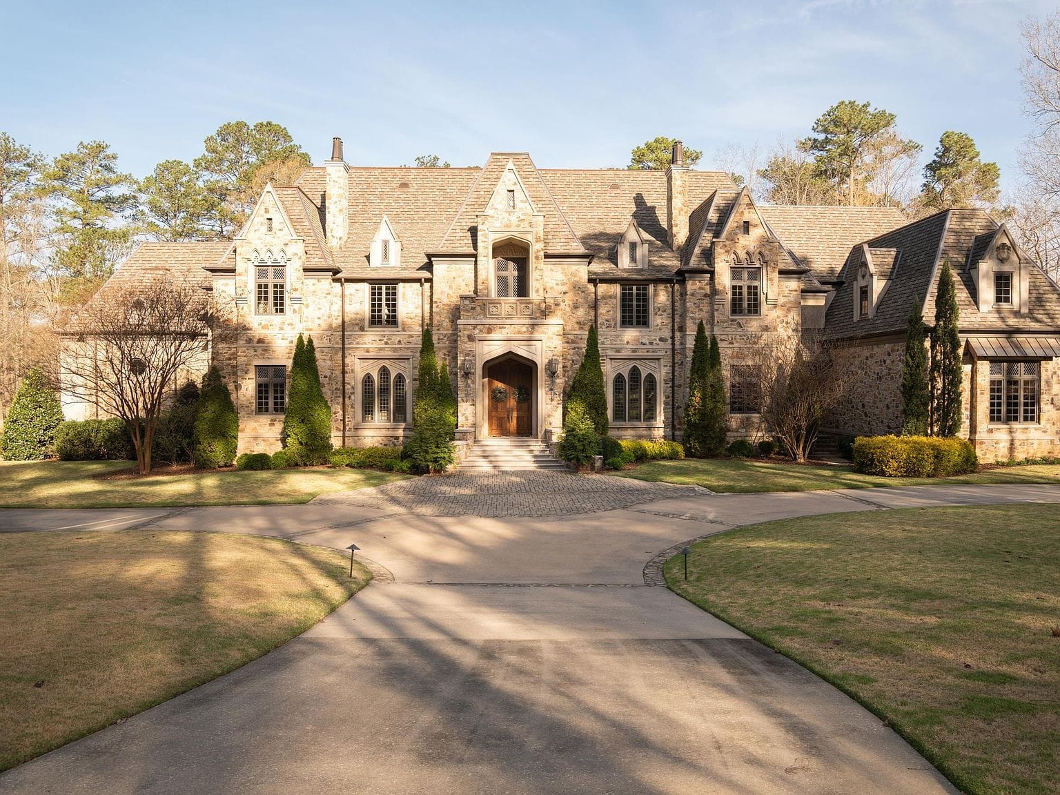 The massive stone exterior of the home with a circular driveway