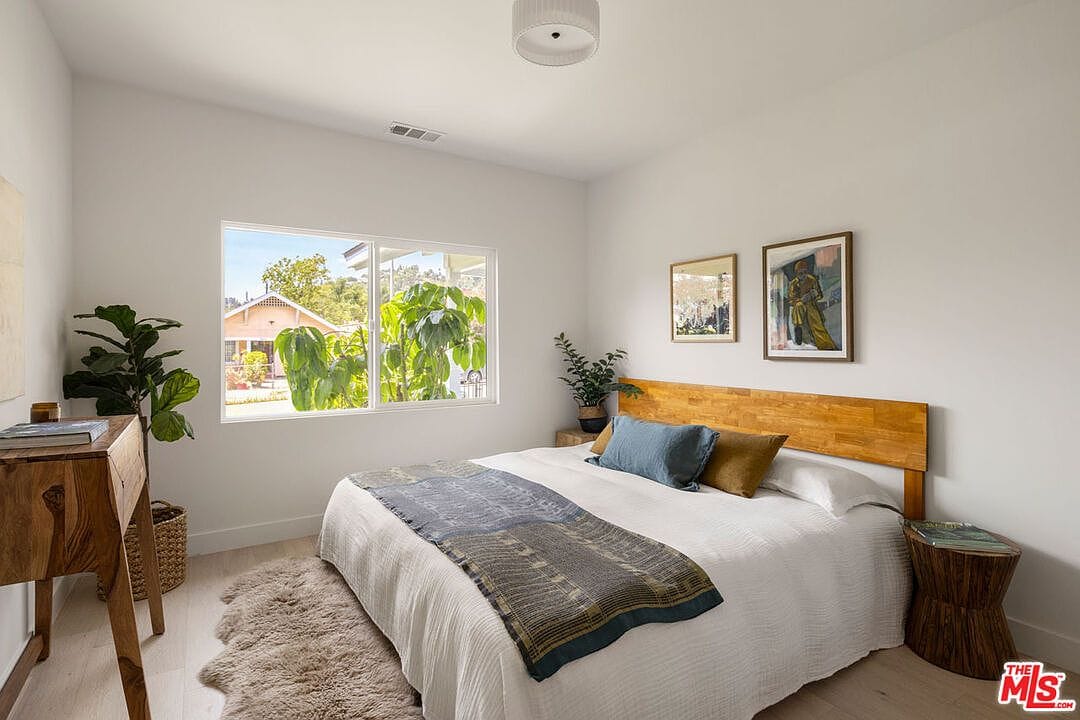 Bedroom with a wooden headboard, white bedding, and large window