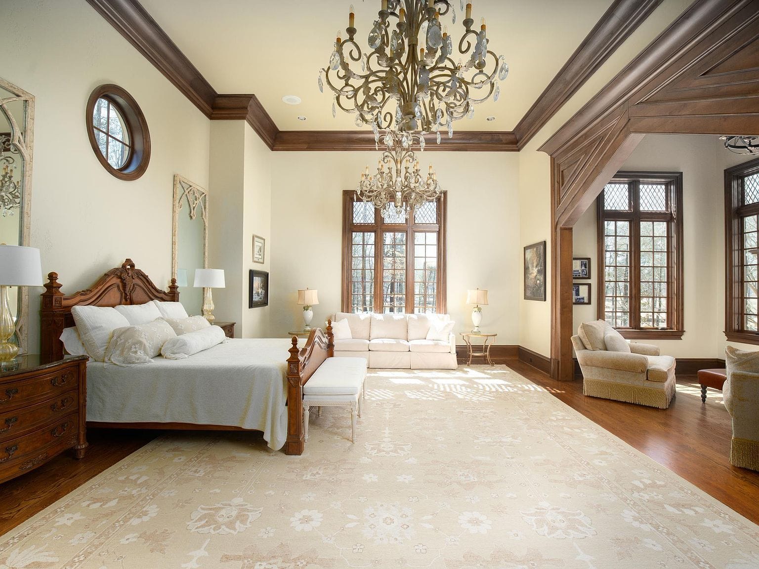 The grand primary bedroom with white walls and a large wooden bed