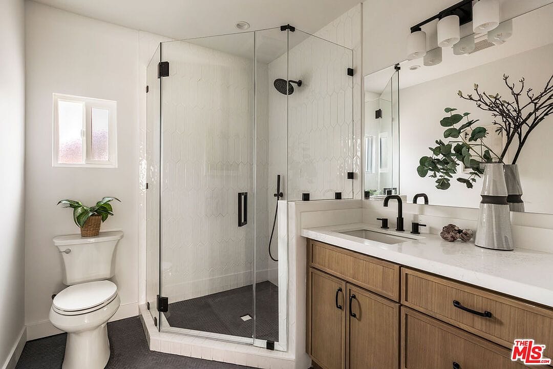 Bathroom with a glass corner shower, wood vanity, and black fixtures