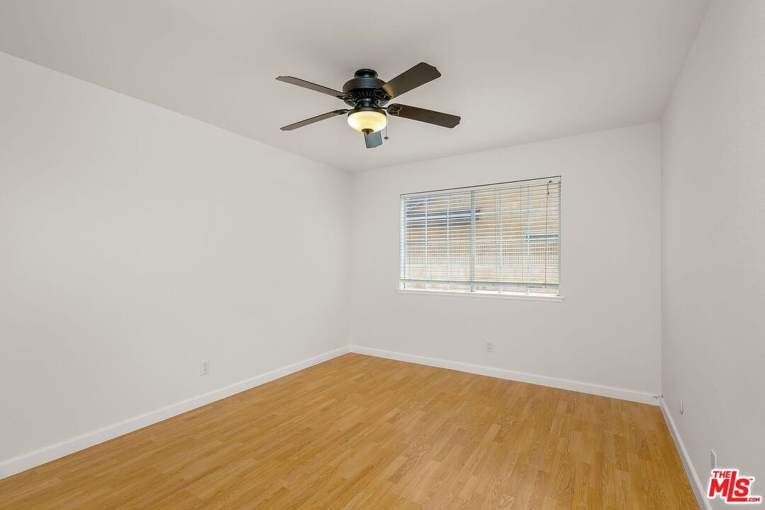 Empty downstairs bedroom with wood flooring and ceiling fan