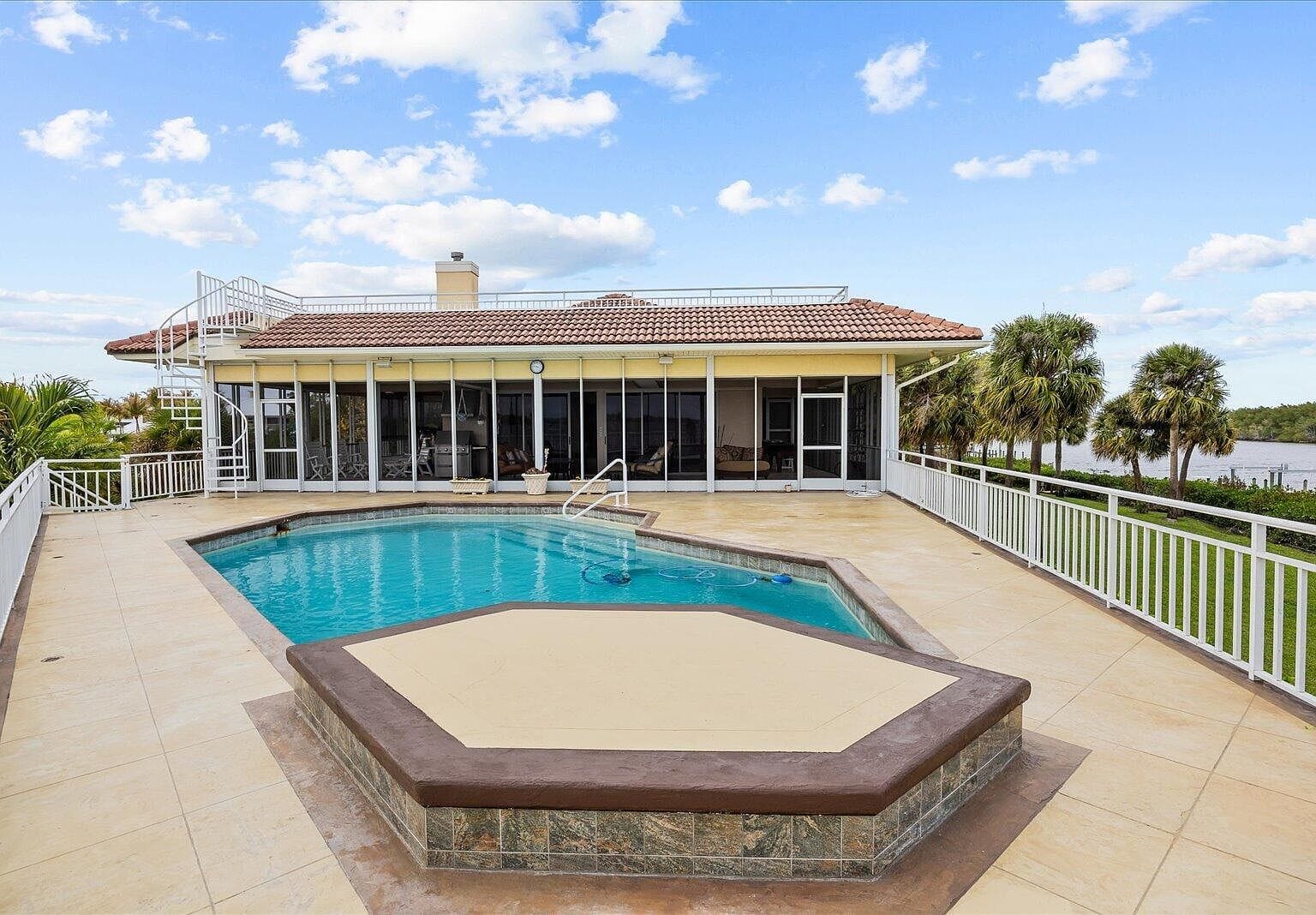 Large concrete pool deck with a custom pool and spa