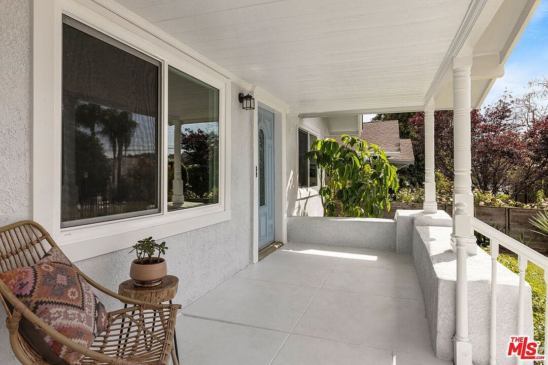 Front porch with white pillars, concrete floor, and light blue door