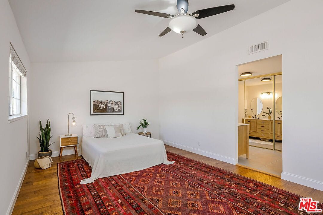 Large primary bedroom with a red rug and wooden floors