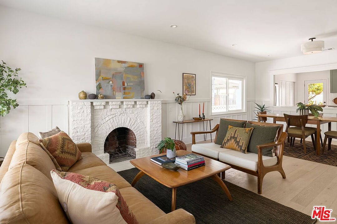 Living room with a brick fireplace, leather couch, and wooden coffee table