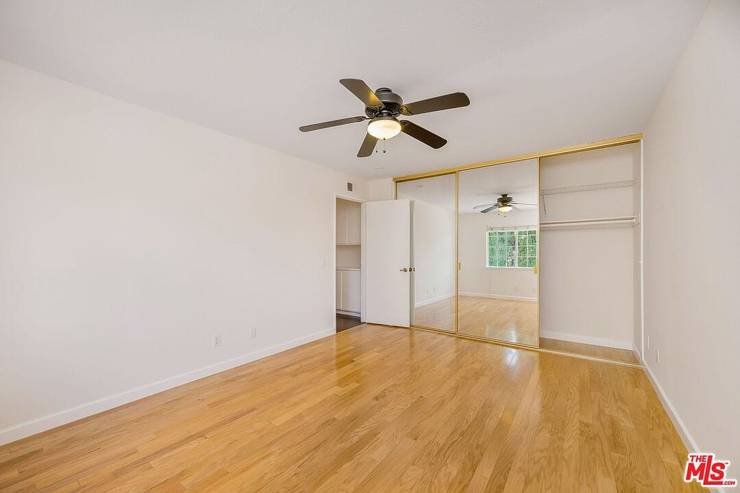 Wide view of empty bedroom with mirrored closet doors