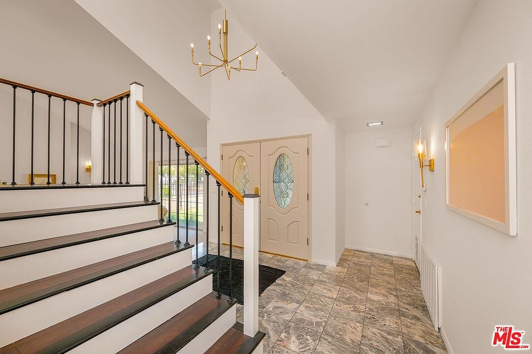 Foyer with stone tile floors and wooden staircase
