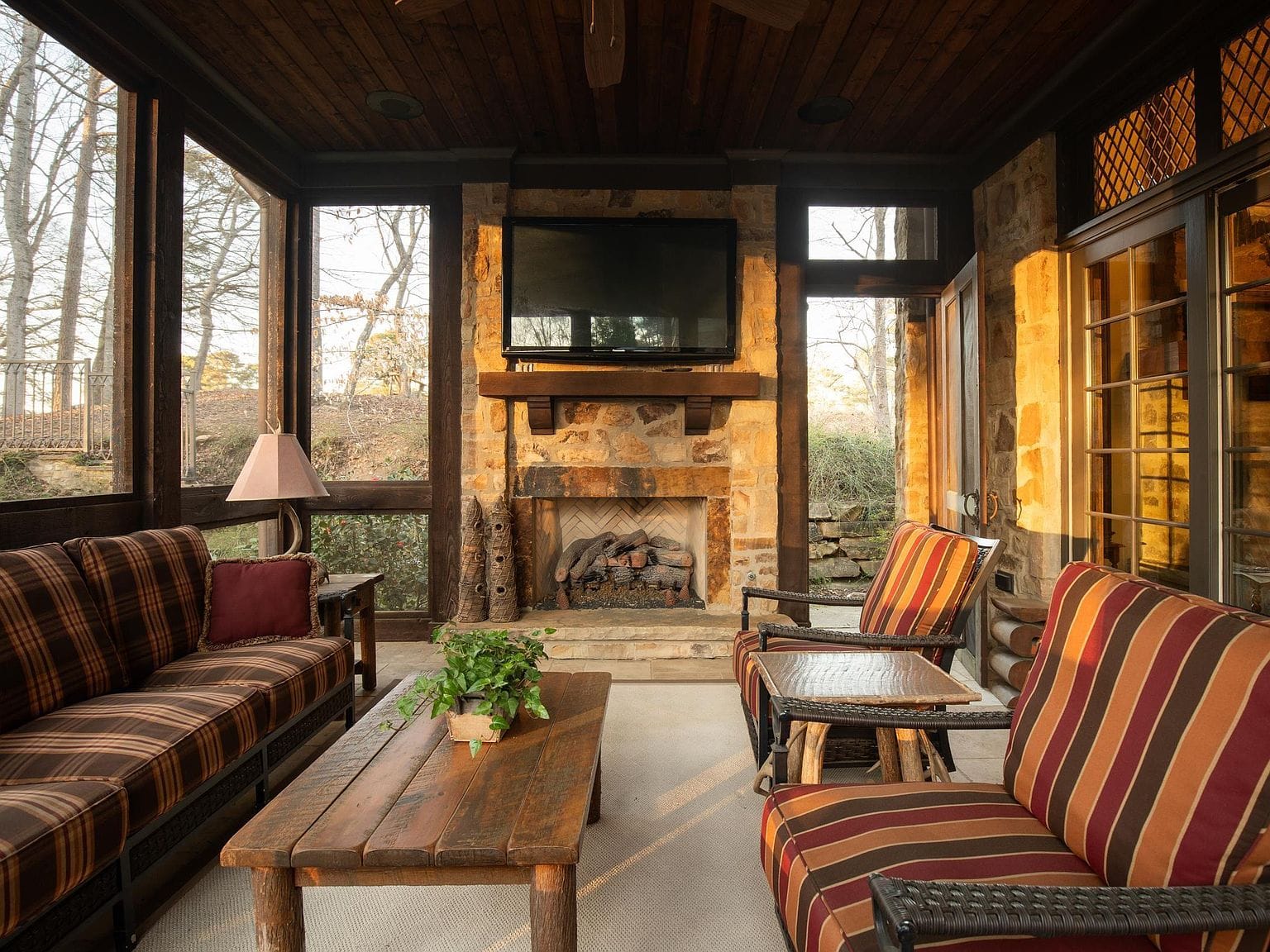 A screened-in porch with a stone fireplace and comfortable seating