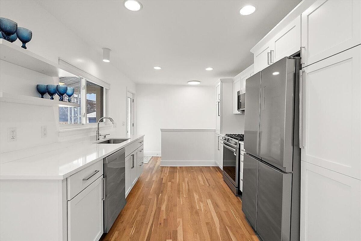 Empty kitchen view looking toward the refrigerator and back hallway
