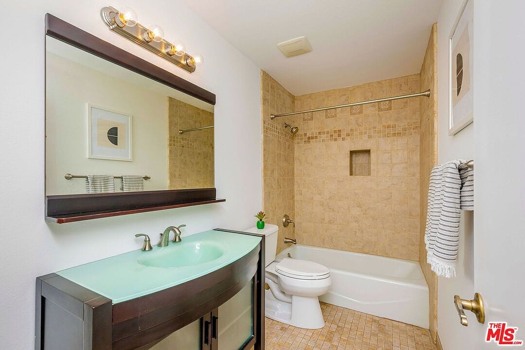 Hallway bathroom with a unique green glass sink vanity