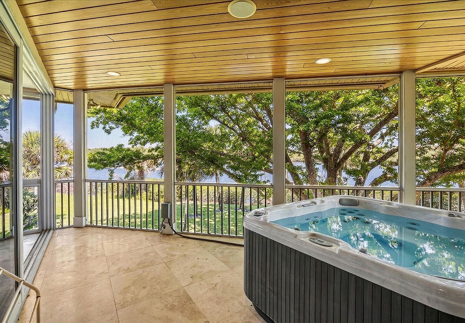 Grey hot tub on a screened balcony overlooking the water