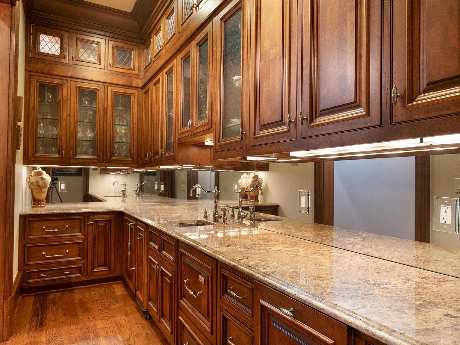A butler pantry with dark wood cabinets and stone countertops