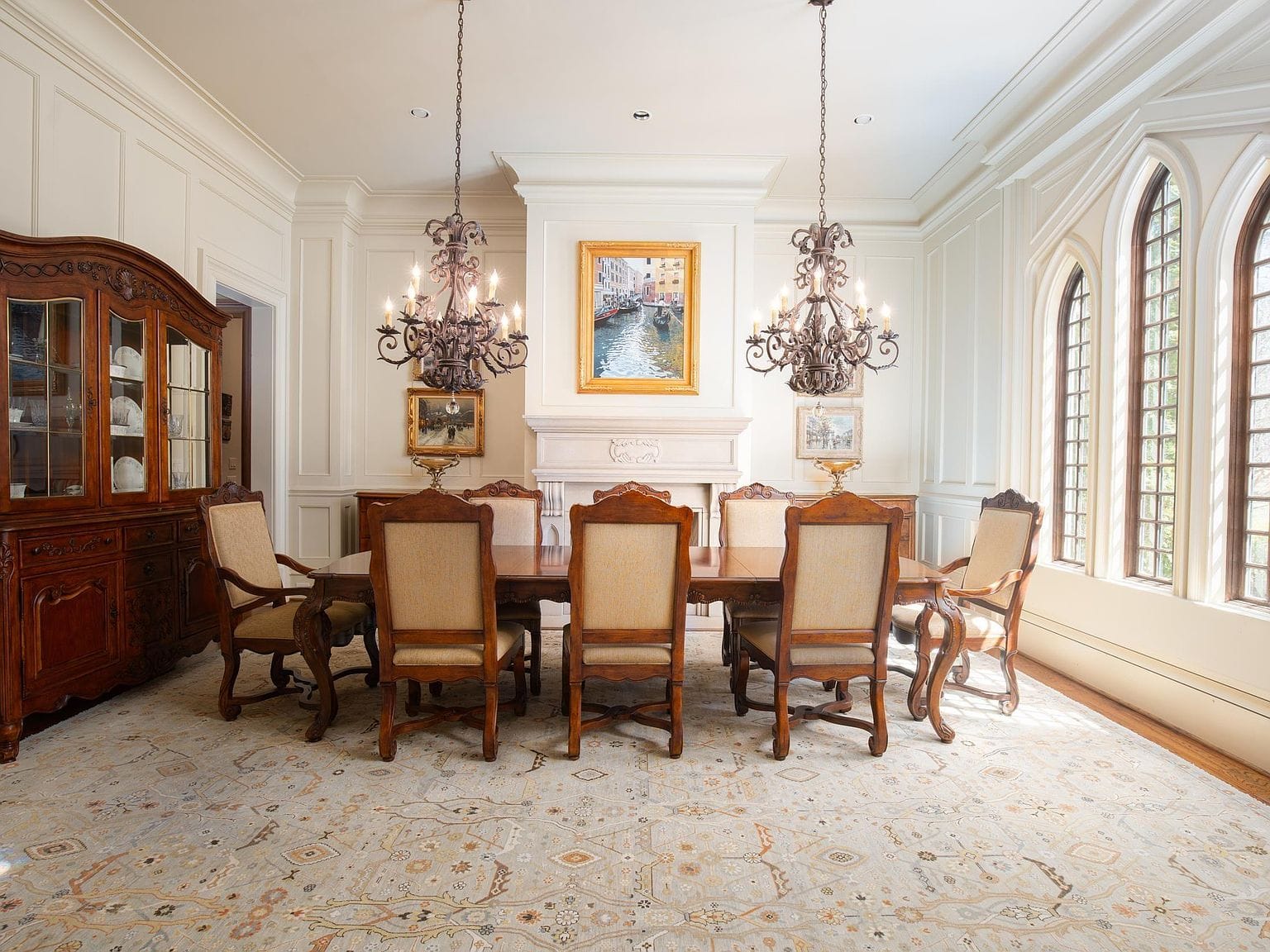 A large formal dining room with wood paneling and two chandeliers