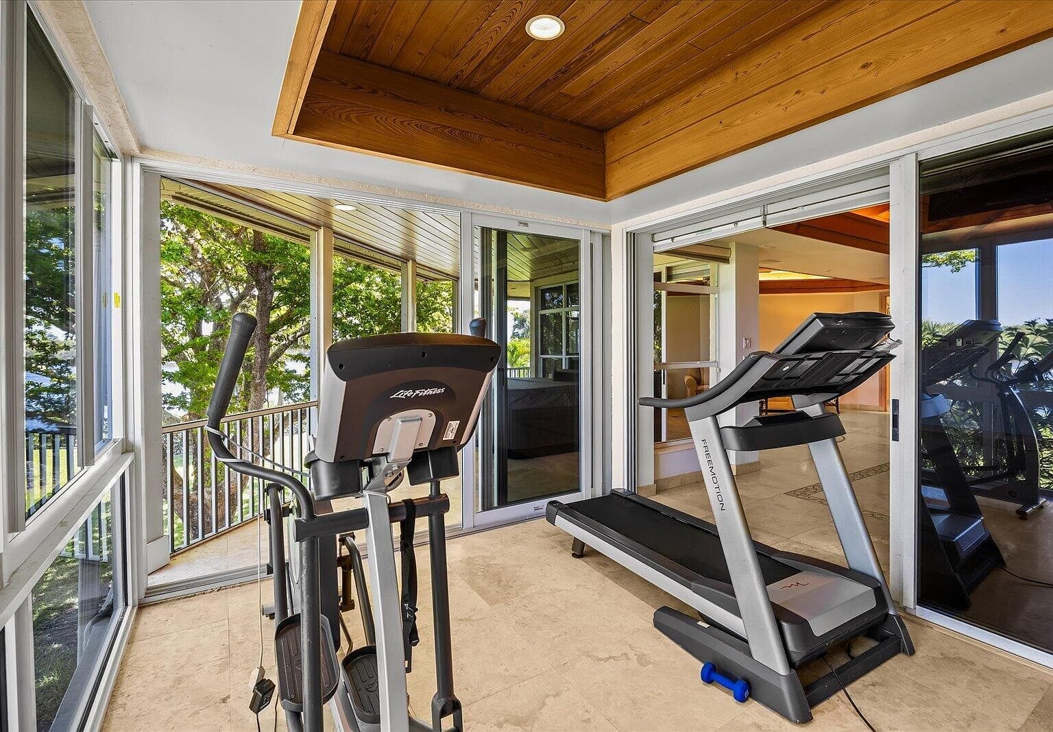 Home gym room with workout equipment overlooking the trees and river