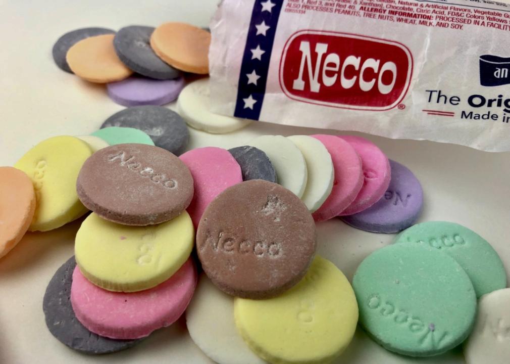 Necco wafers A bag with the words "Necco" surrounded by round colorful cookies with necco lettering on them.
