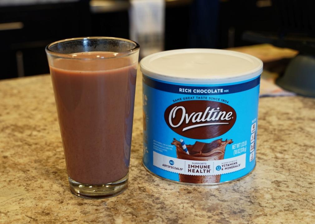 Ovaltine Ovaltine rich chocolate milk mix and a glass of milk sit on kitchen countertop.