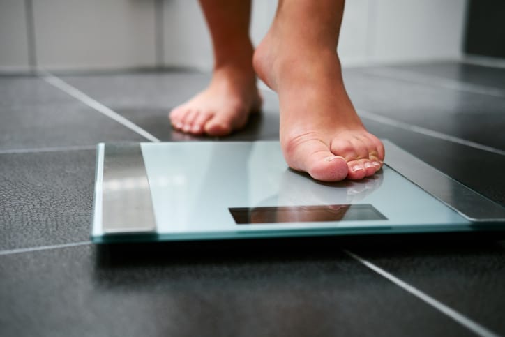 person stepping on a scale showing weight loss