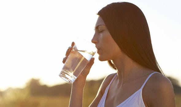 person drinking a large glass of water