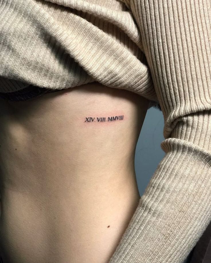 a rib tattoo with a roman numeral date