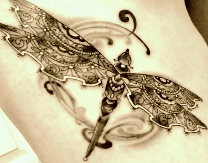 a ribs tattoo with intricate dragonfly wings