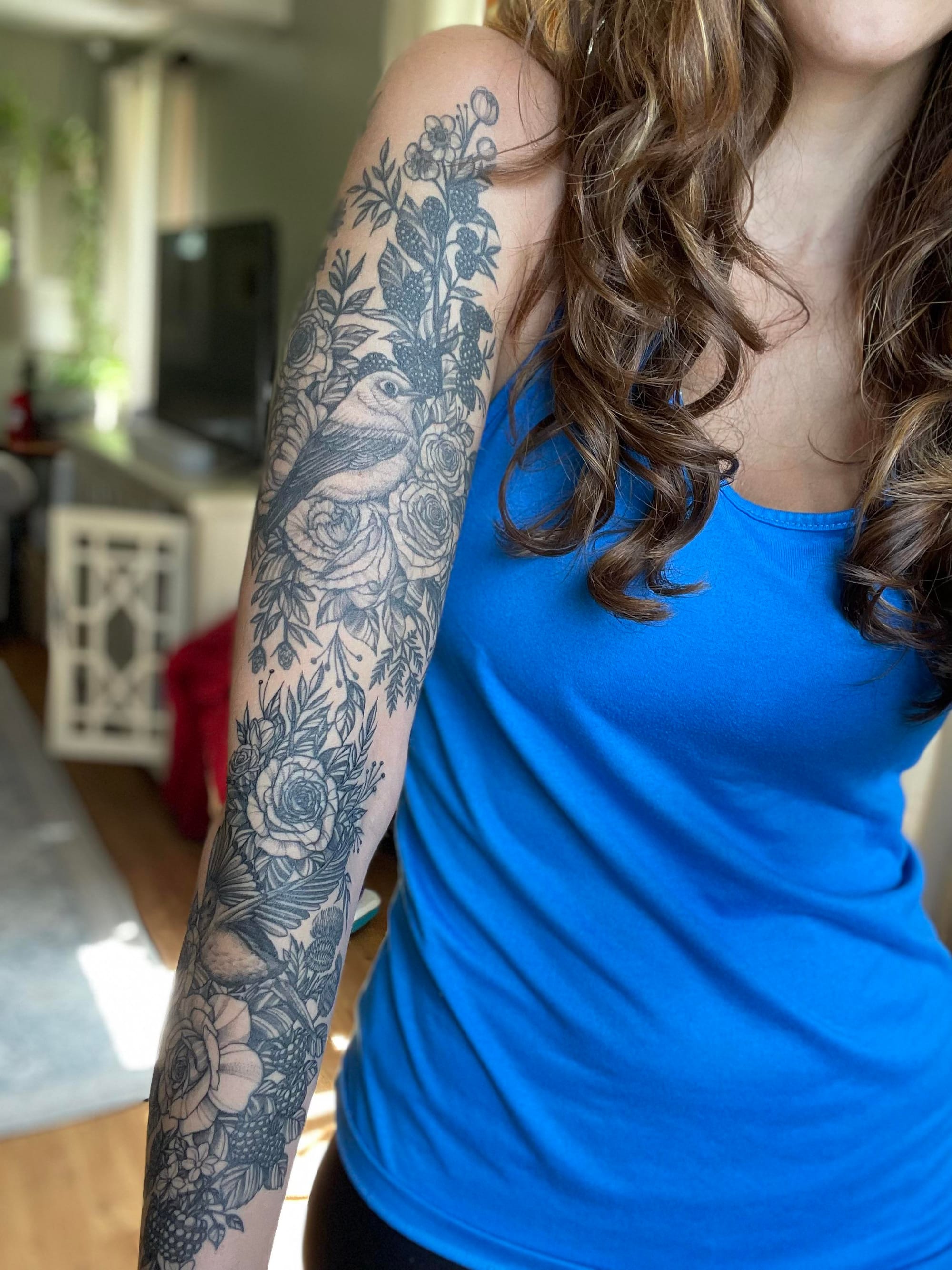 Botanical artistry blooms across this stunning full sleeve, where delicate roses intertwine with flowing foliage in exquisite black and grey detail. The intricate linework creates a garden tapestry that wraps seamlessly from shoulder to wrist, showcasing how floral tattoos can be both feminine and boldly statement-making 🌹