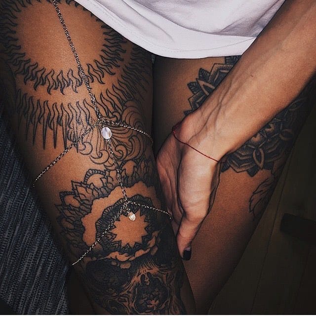 Intricate mandala blooms cascade down these thighs in stunning blackwork detail, creating a mesmerizing garden of geometric petals and sacred symbols. The delicate body chain weaving through this botanical masterpiece adds an extra layer of feminine mystique, perfectly complementing the tattoo's spiritual energy ✨