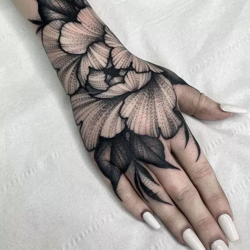 Delicate dotwork petals cascade across this hand like fallen cherry blossoms, creating an ethereal sleeve that flows seamlessly from wrist to fingertips. The intricate stippling technique adds incredible depth and texture, making each flower appear to float just beneath the skin. Bold black linework grounds the design while maintaining its dreamy, botanical elegance 🌸