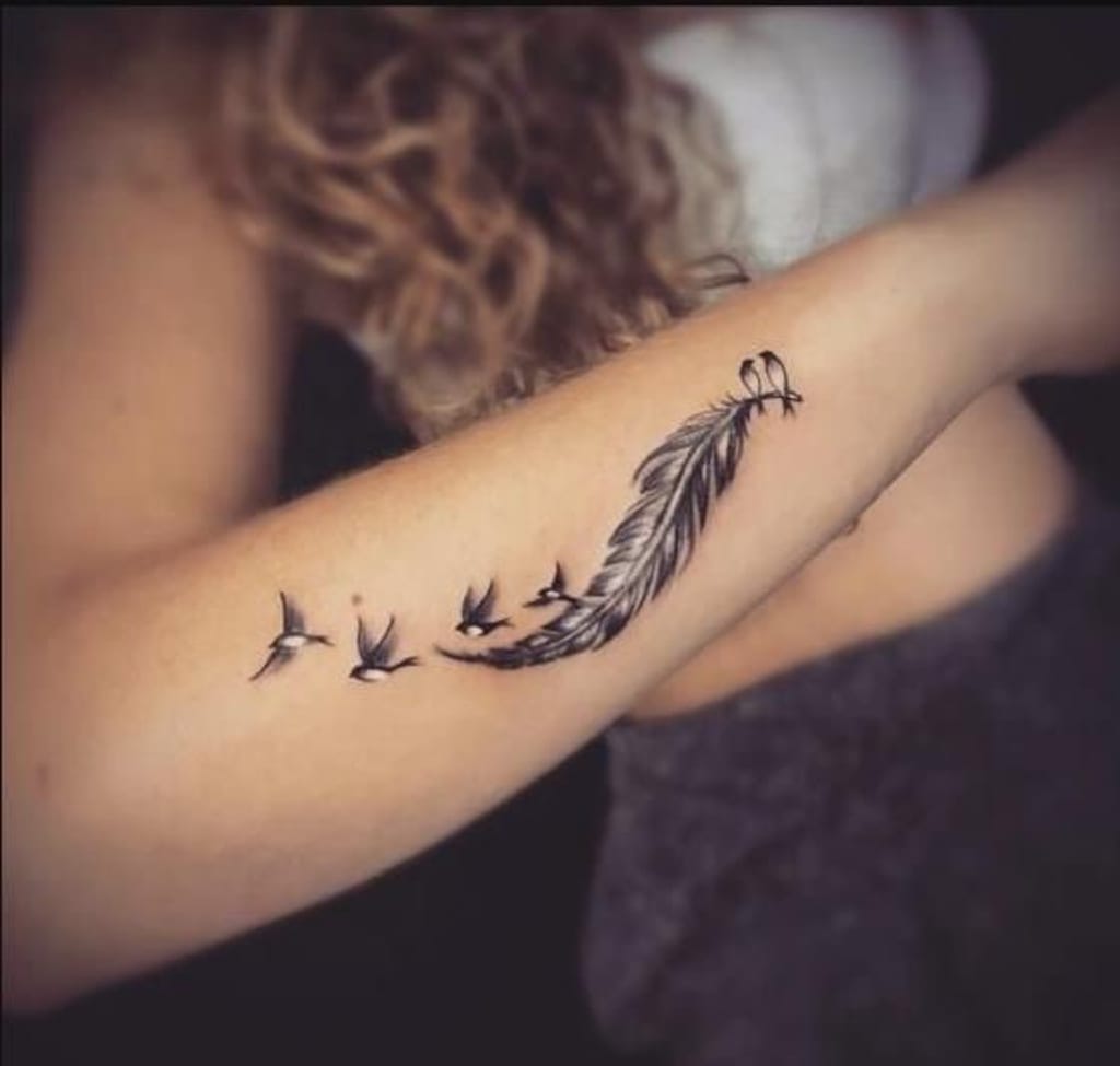 Delicate birds take flight from an intricately detailed feather in this stunning forearm piece that captures pure movement and grace. The flowing composition creates a beautiful narrative of transformation and freedom, with each tiny bird rendered in perfect silhouette against the skin. ✨ A timeless design that speaks to the soul's desire to soar.