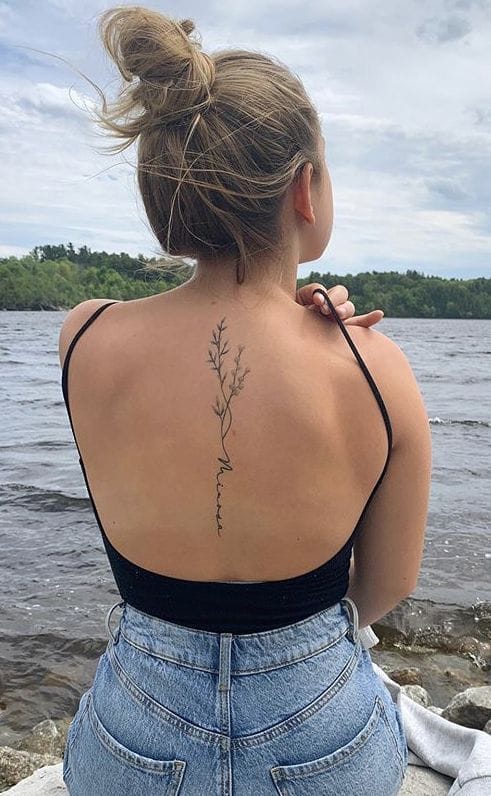 Delicate botanical artistry flows down this woman's spine like nature's own calligraphy, creating an elegant vertical garden against sun-kissed skin. The minimalist line work and organic placement transform her back into a living canvas where simplicity meets profound beauty 🌿