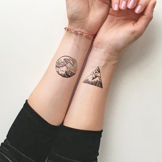 Nature's eternal dance captured in complementary ink—one wrist showcases Hokusai's iconic wave within a perfect circle, while its partner displays a geometric mountain peak trapped in a triangle. The matching forearm placement creates beautiful symmetry that celebrates both the fluidity of water and the steadiness of earth 🌊⛰️