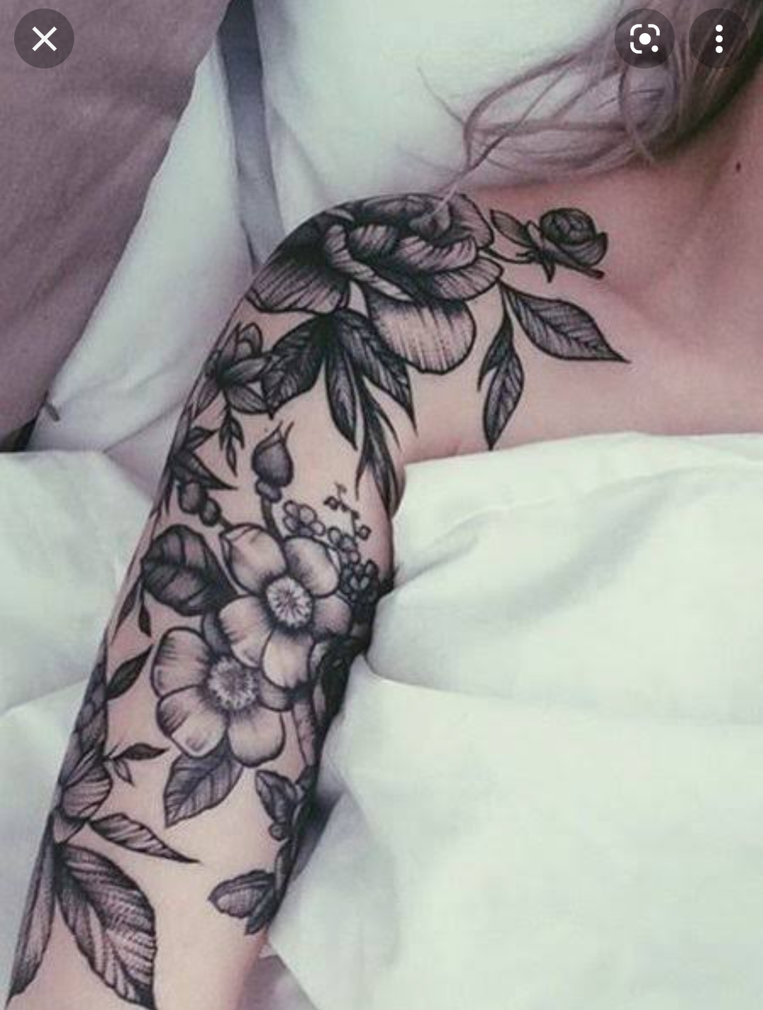 Delicate botanical artistry flows seamlessly from shoulder to forearm in this stunning black and grey floral sleeve. The intricate line work and soft shading create beautiful depth across roses, wildflowers, and trailing foliage that seems to dance along the arm's natural curves. A perfect example of how feminine florals can make such a bold, elegant statement 🌿