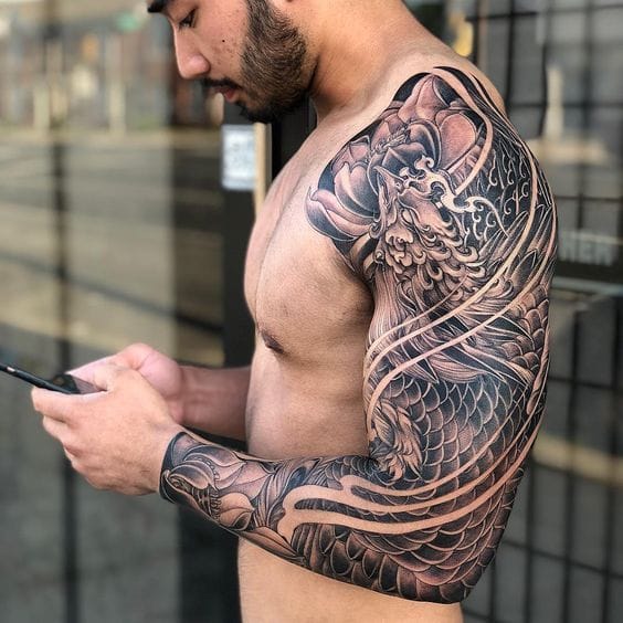 Flowing seamlessly from shoulder to wrist, this masterful dragon sleeve captures the essence of Japanese irezumi artistry with its bold black linework and intricate scale details. The mythical creature appears to coil around the arm in perpetual motion, its fierce expression and flowing mane creating a striking contrast against the skin 🐉 The technical precision of the shading and the way it follows the natural contours of the musculature makes this piece a true wearable masterpiece.
