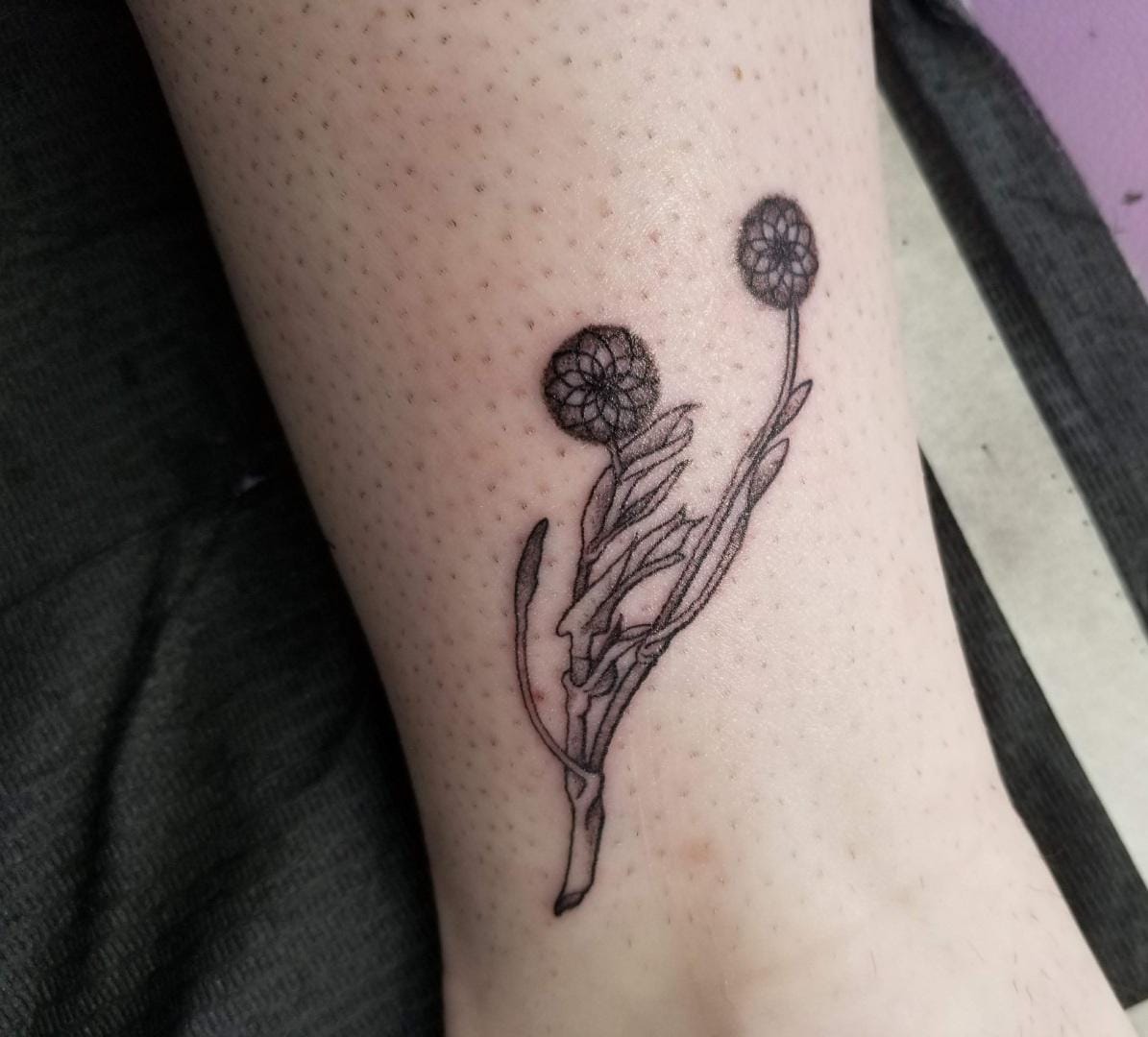 Delicate line work brings this botanical beauty to life, featuring two spherical blooms that dance along the forearm like nature's own geometric art. The intricate crosshatched pattern within each flower head creates stunning texture and depth, while flowing stems and leaves add organic movement to this minimalist masterpiece. 🌿 Perfect placement allows the design to follow the natural curve of the arm, making it feel like a living extension of the wearer's body.