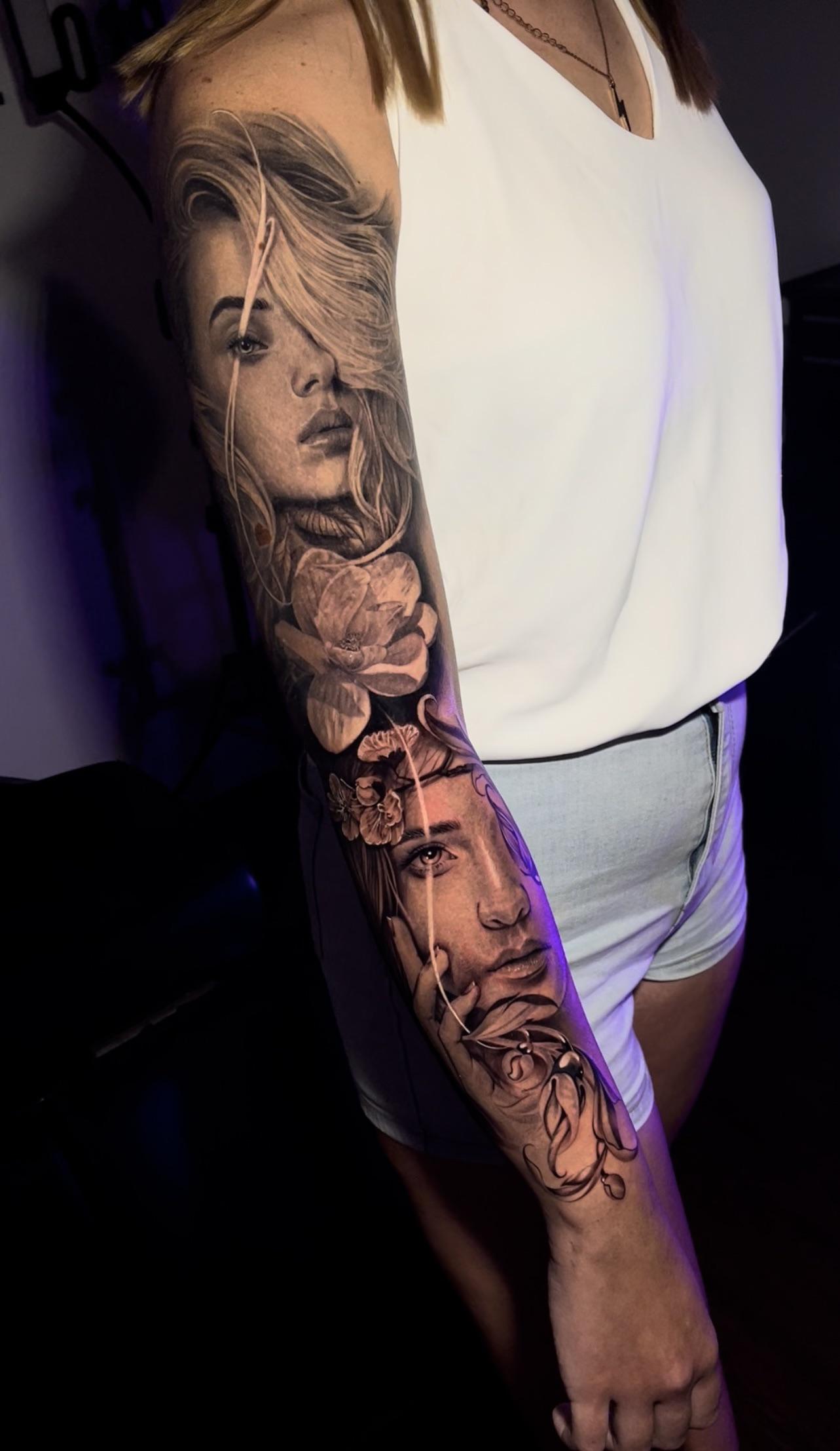 Masterful realism flows down this full sleeve, showcasing two ethereal portraits intertwined with delicate roses in stunning black and grey detail. The artist's incredible skill shines through every strand of hair and petal, creating a hauntingly beautiful composition that transforms the entire arm into a living canvas. Pure artistry that proves tattoos are truly wearable masterpieces ✨