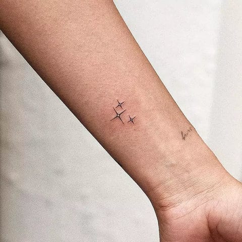 Three delicate stars dance across this wrist in perfect minimalist harmony, their fine-line artistry proving that sometimes the smallest details make the biggest statement. The precise placement along the inner forearm creates an intimate constellation that catches light beautifully with every gesture ✨