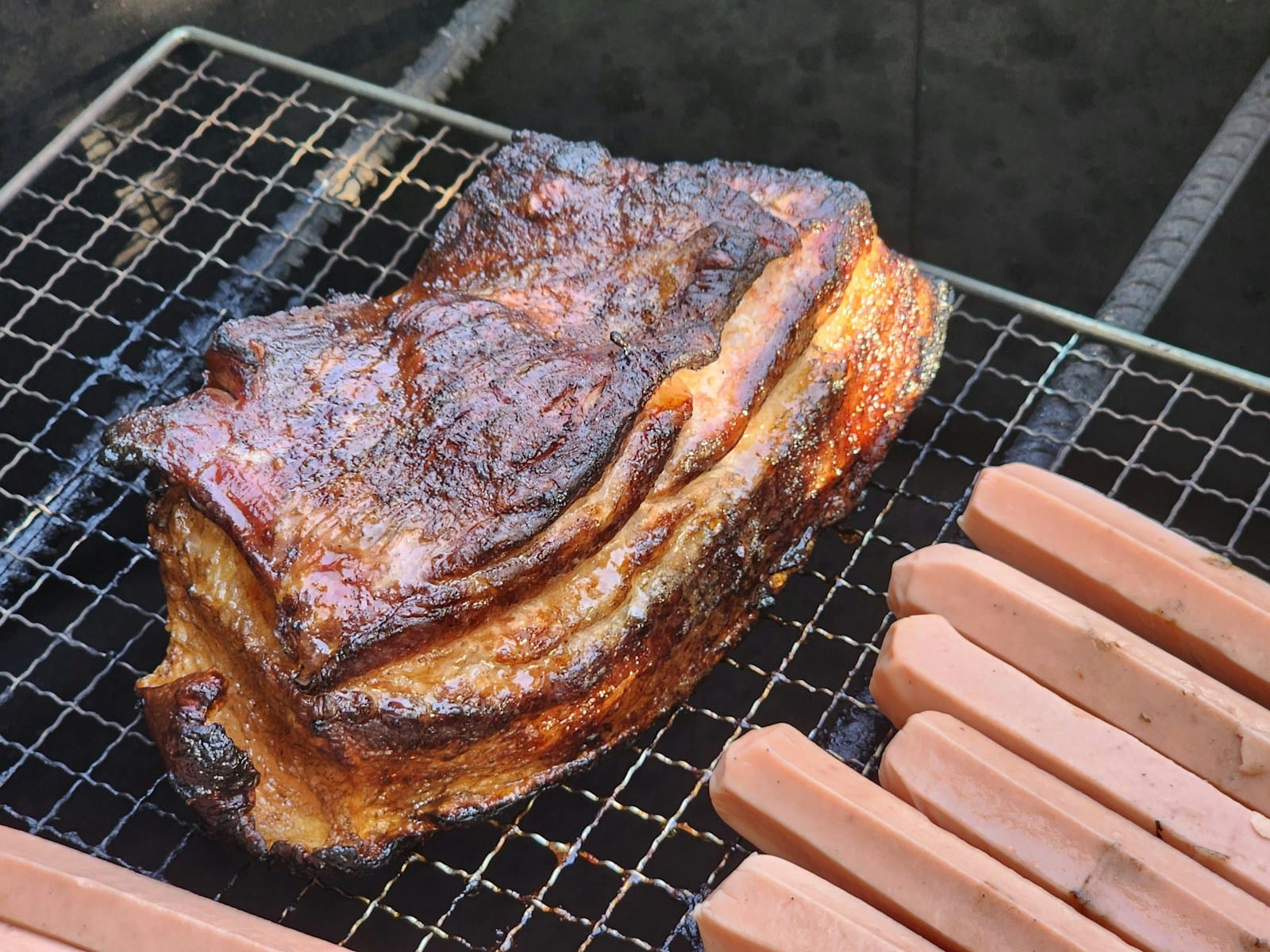 a steak and hotdogs are cooking on a grill