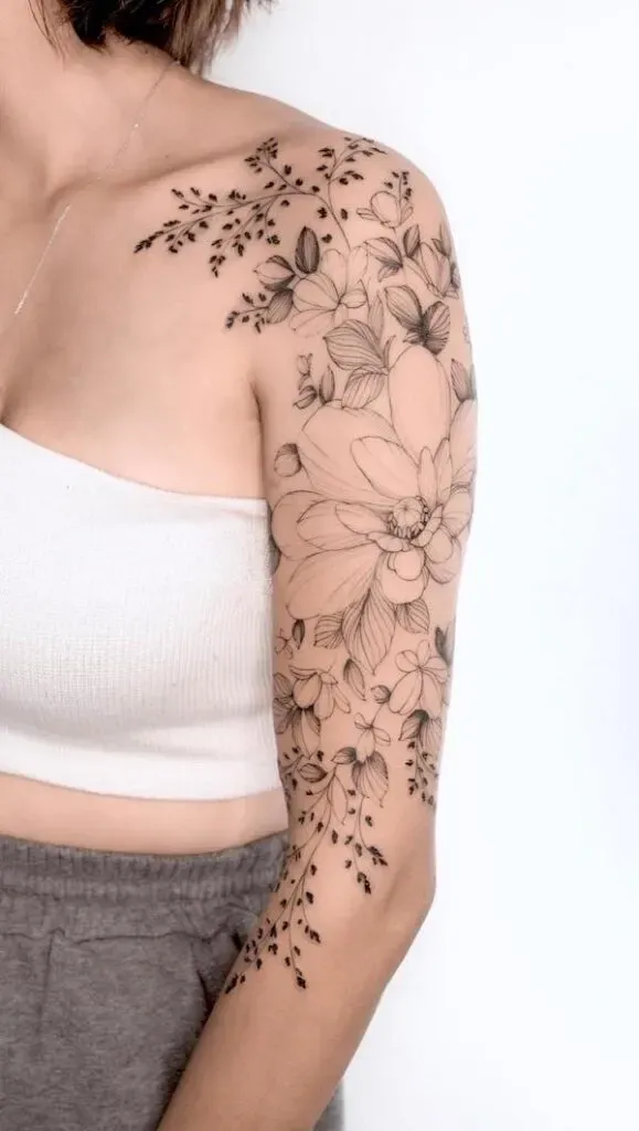Cascading from shoulder to forearm, this botanical masterpiece transforms the entire arm into a living garden 🌸 The delicate line work captures every petal and leaf with stunning precision, while the flowing composition follows the natural curves of the body. A perfect example of how floral tattoos can be both feminine and bold, creating an elegant sleeve that feels like wearable art.