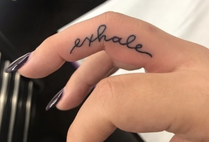 Delicate script flows across knuckles like a gentle reminder written in ink, transforming fingers into a canvas for mindful living. The word