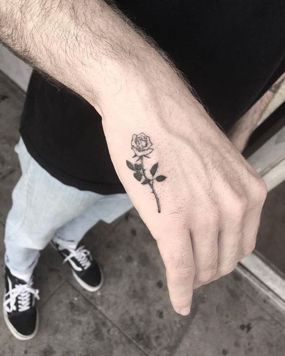 Delicate black ink brings this single-stem rose to life on the back of the hand, creating an unexpectedly romantic statement piece. The fine line work and strategic placement make it visible yet subtle, perfect for someone who wants their ink to spark conversations 🌹 The minimalist approach proves that sometimes less really is more when it comes to meaningful body art.