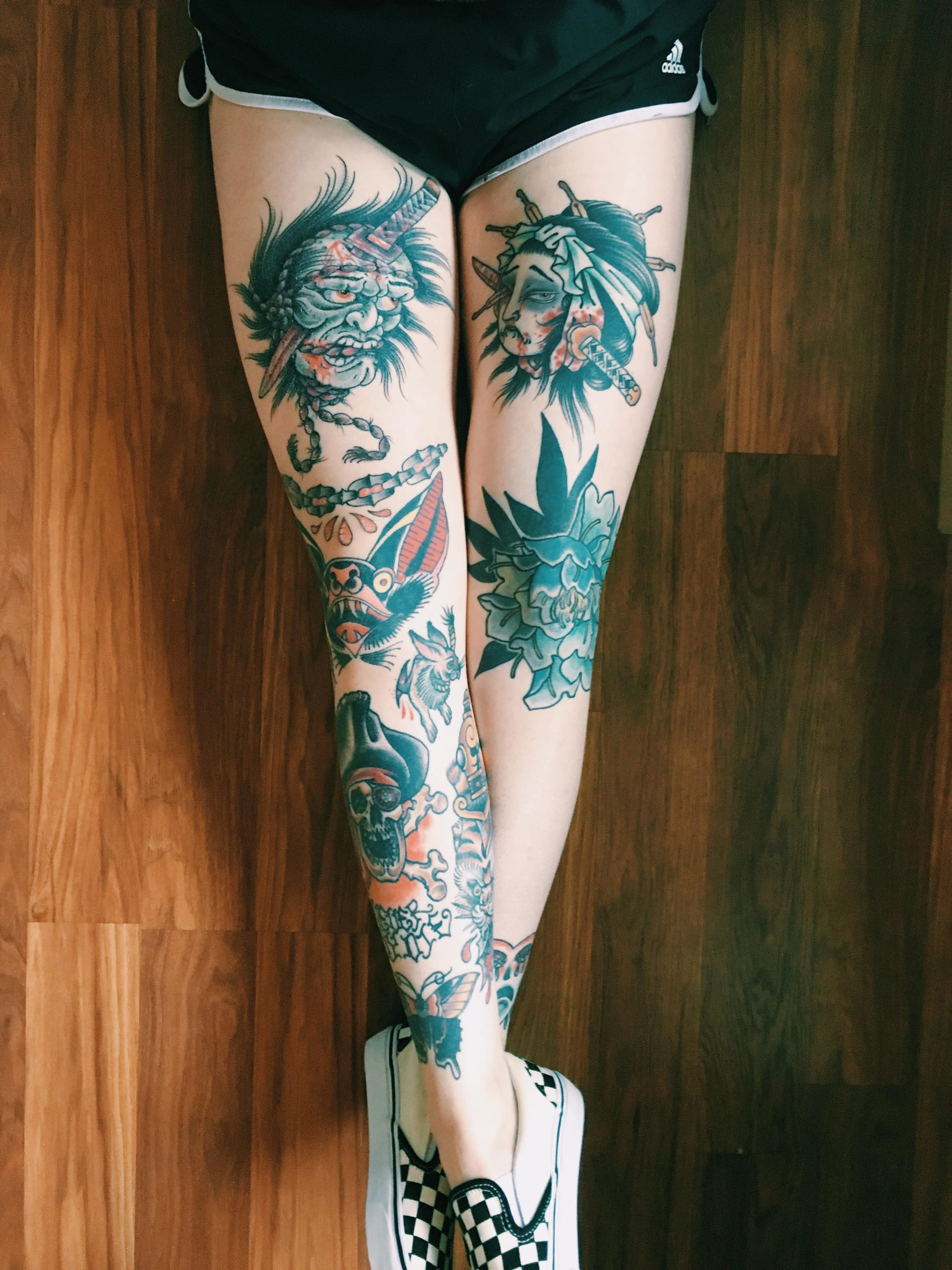 Fierce Japanese mythology comes alive across these incredible leg sleeves, where dragons, oni masks, and traditional motifs create a stunning visual narrative from thigh to ankle. The artist's masterful use of teal and coral accents against bold black linework showcases classic irezumi style at its finest 🐉 Notice how the designs flow seamlessly around the natural curves of the legs, creating perfect symmetry while maintaining each piece's individual character.