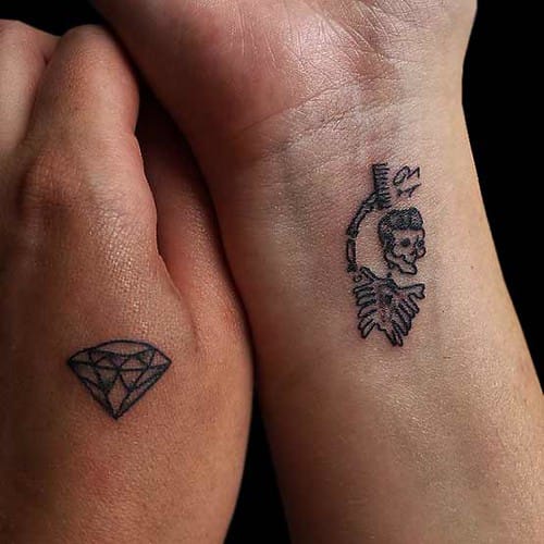 Delicate hand-poked artistry transforms these wrists into a stunning duality - one adorned with geometric diamond precision, the other featuring an intricate skeletal figure that dances between life and death. The contrast between sharp crystalline edges and flowing organic curves creates a mesmerizing visual dialogue about precious beauty and mortality's embrace. 💎