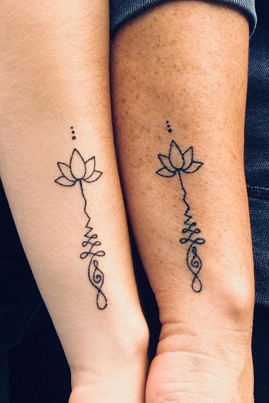 Delicate matching lotus flowers bloom into elegant script on these forearms, creating a beautiful symmetry between two people who clearly share a deep connection. The minimalist line work transforms the sacred lotus symbol into flowing calligraphy, while tiny dots above each flower add a celestial touch that makes this couple's ink feel both grounded and transcendent. 🪷