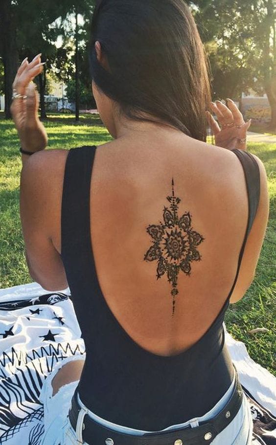 Delicate mandala petals bloom along this woman's spine, creating a stunning vertical centerpiece that transforms her back into living art. The intricate henna-style linework flows gracefully from shoulder blade to lower back, perfectly complementing the natural curve of her silhouette. ✨ A masterpiece of placement that proves sometimes the most elegant tattoos are the ones that work in harmony with your body's natural beauty.