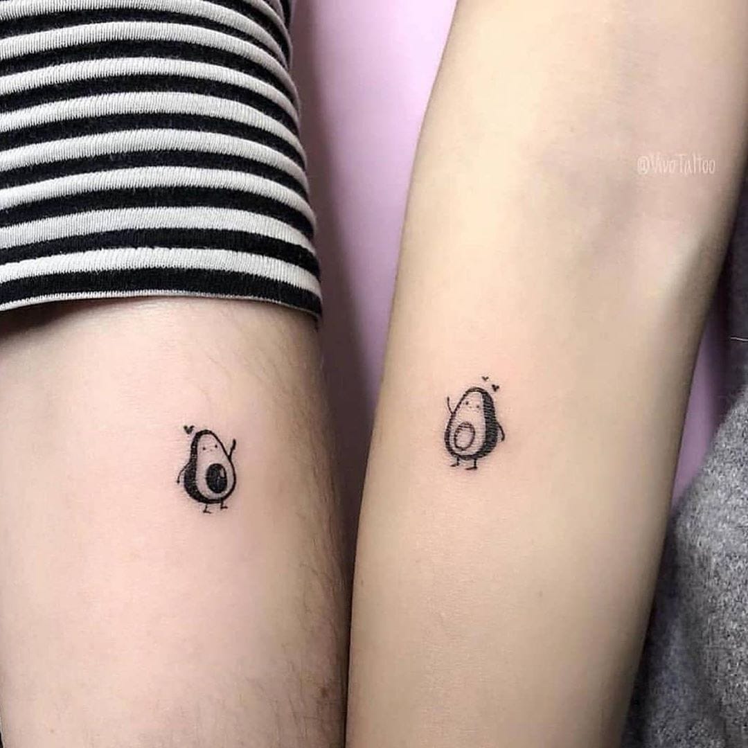 Adorable avocado companions create the sweetest friendship bond across two arms 🥑 These minimalist matching tattoos feature charming cartoon avocados with tiny stick limbs and rosy cheeks, perfectly positioned on the forearms for a delightful reveal when placed side by side. The simple black line work and whimsical expressions capture that