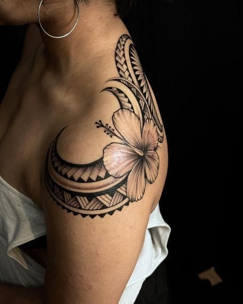 Delicate hibiscus blooms intertwine with bold Polynesian patterns in this stunning shoulder piece that perfectly balances feminine florals with geometric tribal elements. The curved placement follows the natural contours of the shoulder and upper arm, creating a flowing composition that feels both organic and intentionally designed. 🌺