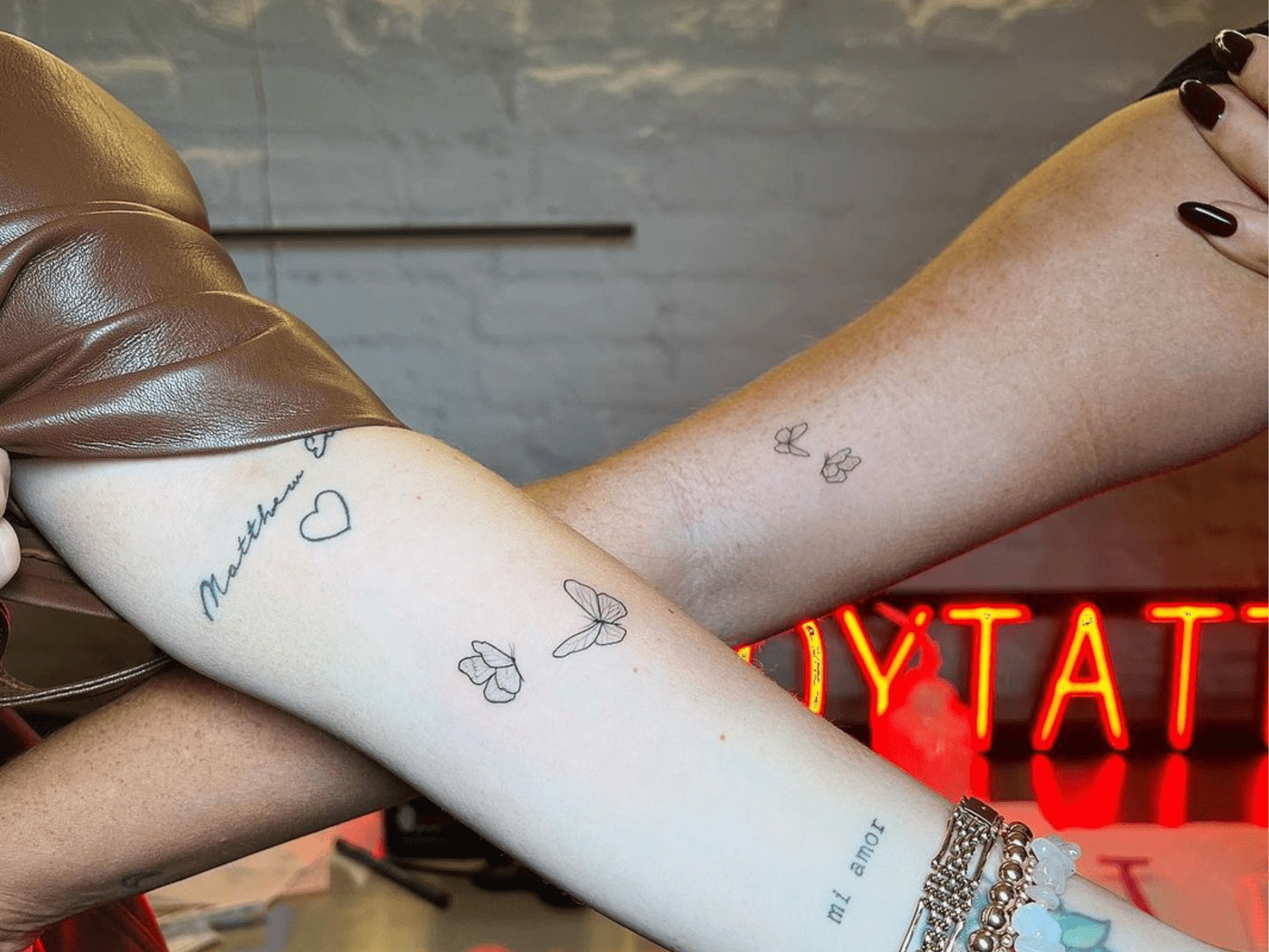 Delicate script flows gracefully across this arm, paired with whimsical butterfly outlines that seem to dance along the skin. The minimal black ink work creates an effortlessly chic aesthetic, while the cursive text adds a personal touch that makes this piece feel like wearable poetry 🦋